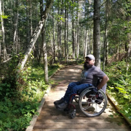 Enock sitting on a boardwalk in his wheelchair