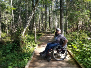 Enock sitting on a boardwalk in his wheelchair